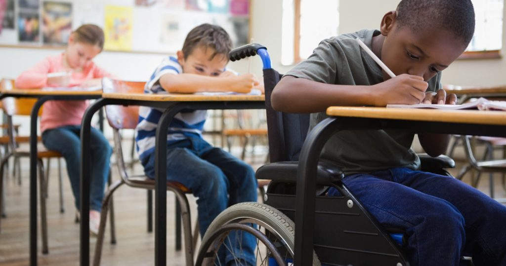 Trois enfants en situation de handicap travaillant dans une salle de classe