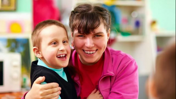 Enfant souriant étant porté par une personne aidante.